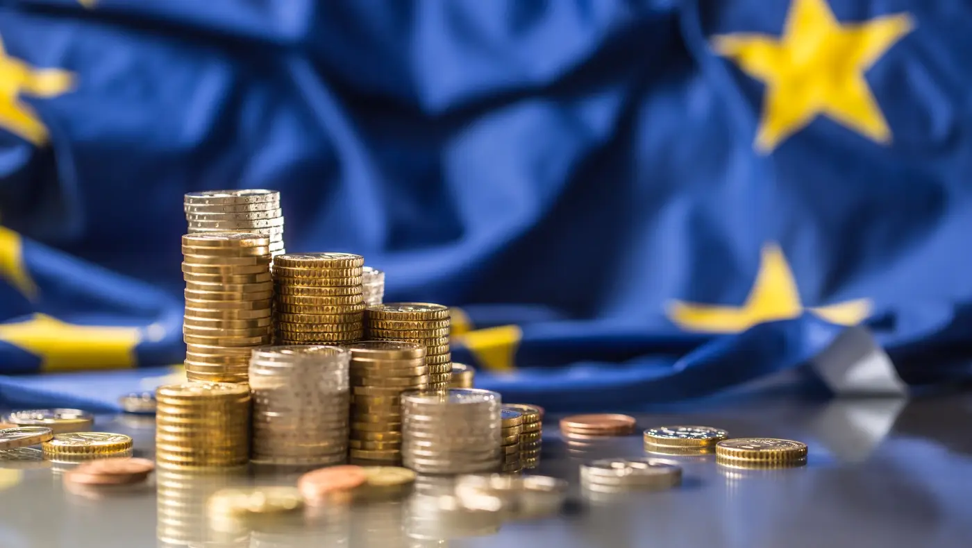 Mince před vlajkou Evropské unie symbolizující pokuty podle GDPR